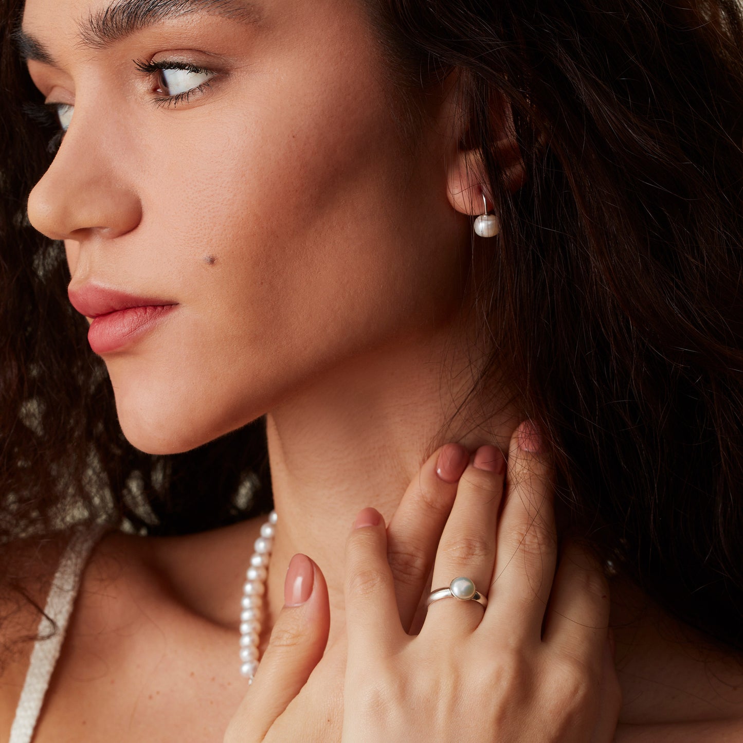 Model wearing matching pearl earrings, pearl ring and pearl beaded necklace