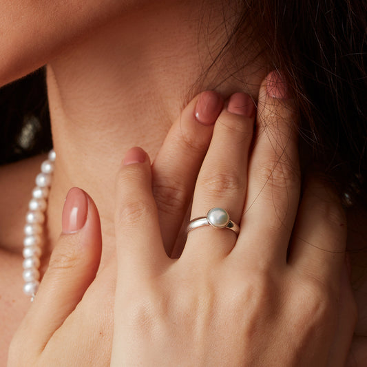 Round pearl and silver ring worn on hand