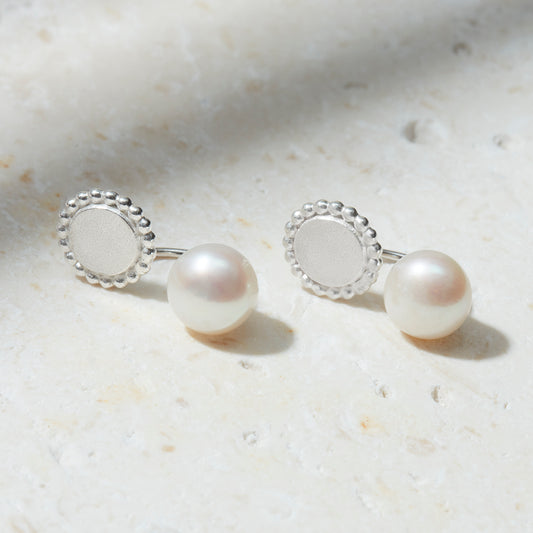 Sterling silver ear jackets with freshwater pearls and a detailed round silver disc with dotted edges.