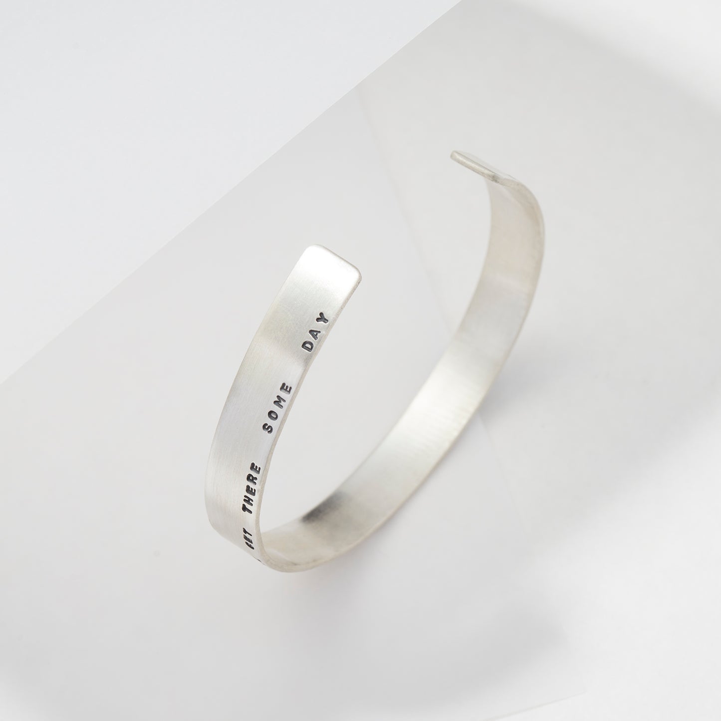 Handcrafted sterling silver arm cuff featuring a custom engraved message, displayed on a minimal white background.