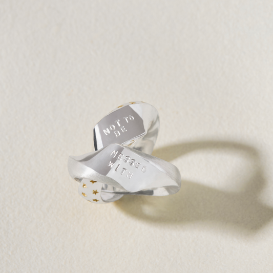 Personalised sterling silver Möbius ring opened to reveal hidden hand-stamped message