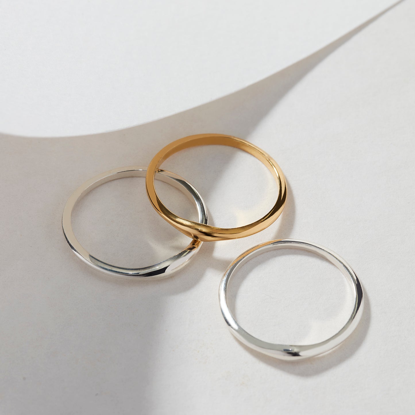 A side profile view of three stacked Slender Ripple Stacking Rings, emphasizing their slender and rippled design in sterling silver and 18ct gold vermeil.
