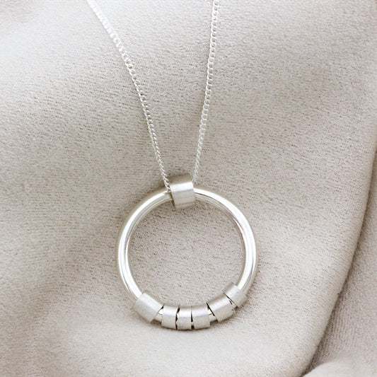 Tactile silver necklace with round hoop pendant and customisable hidden message on spinning beads.