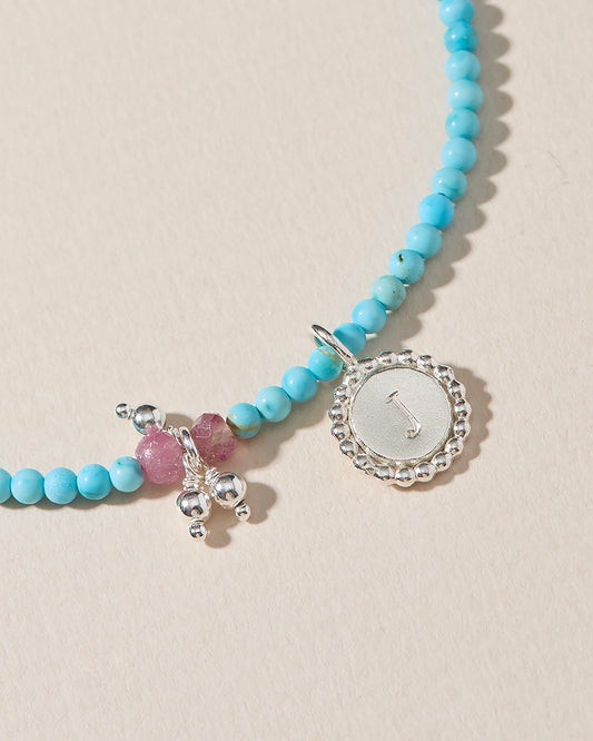 Hand-stamped sterling silver initial pendant on turquoise and pink tourmaline beaded necklace