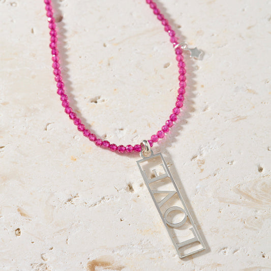 Close-up of openwork sterling silver LOVE pendant on natural ruby beaded necklace