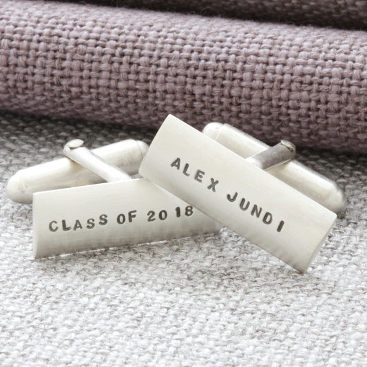 Detailed view of sterling silver cufflinks with personalised engraving. One cufflink says 'Class of 2018' the other says 'Alex Jundi'