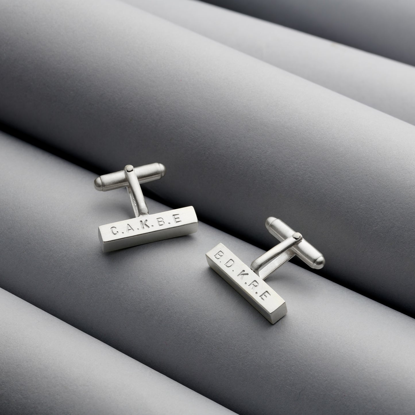 Detailed view of solid silver bar cufflinks with hand-stamped engraving and a satin finish.