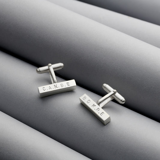 Detailed view of solid silver bar cufflinks with hand-stamped engraving and a satin finish.