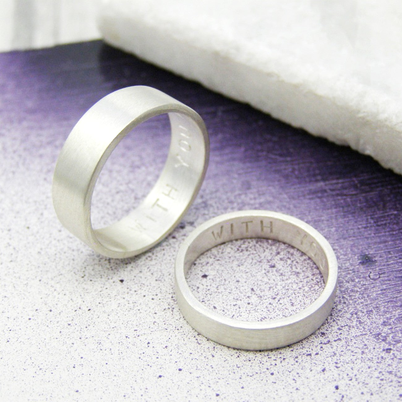 Matching silver rings for couples, featuring hidden messages.