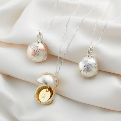 Personalised globe locket necklace open to reveal a hand-stamped initial disc
