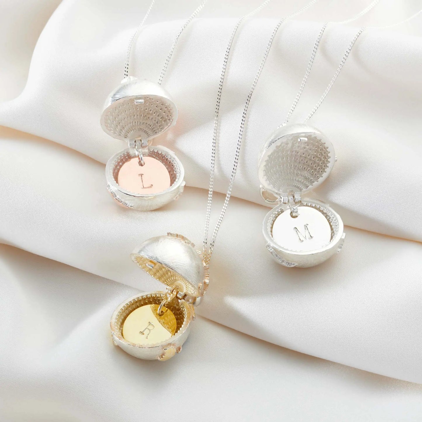 Open personalised globe lockets with hand-stamped initial discs in silver and gold finishes
