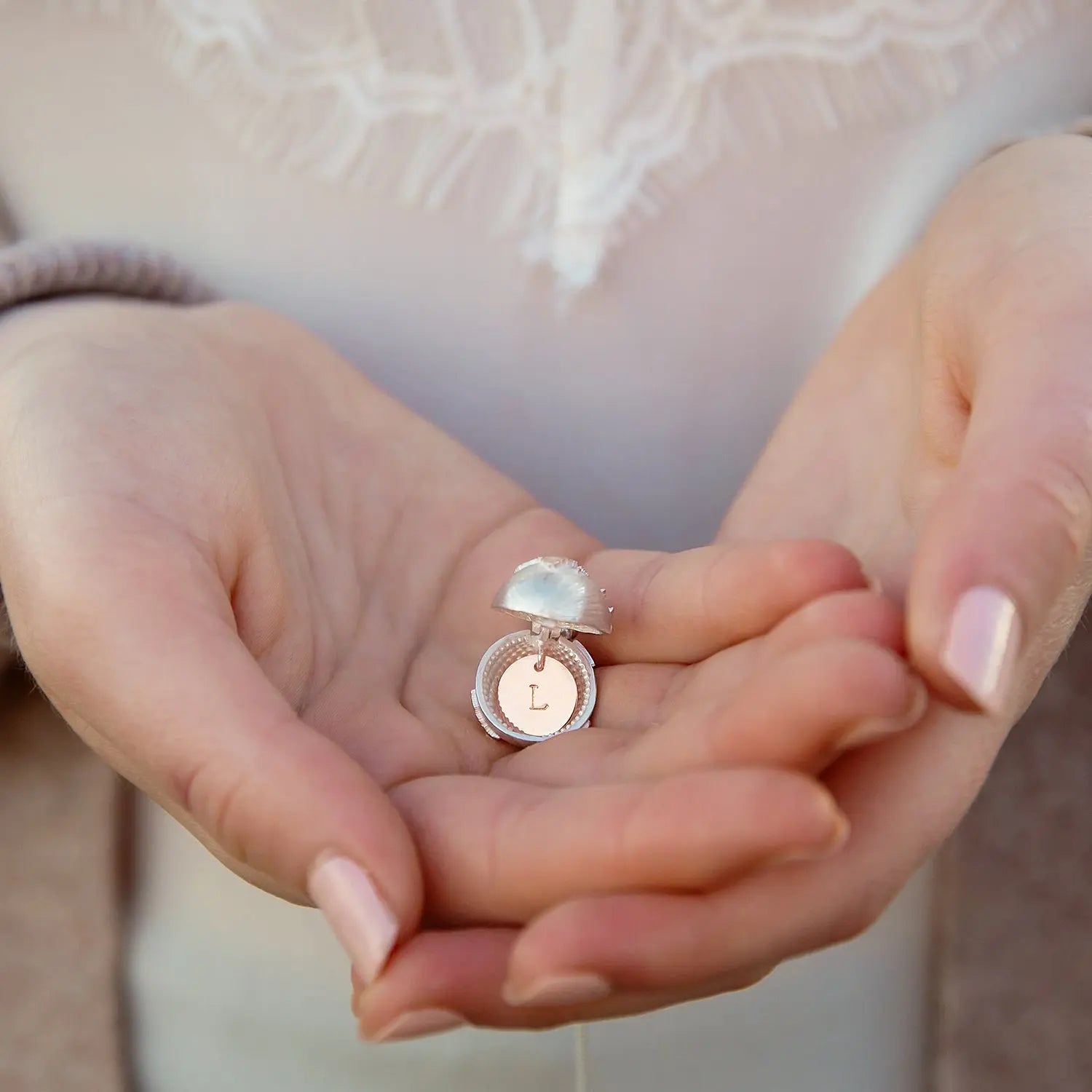 Personalised globe locket held open in hands showing the hidden initial
