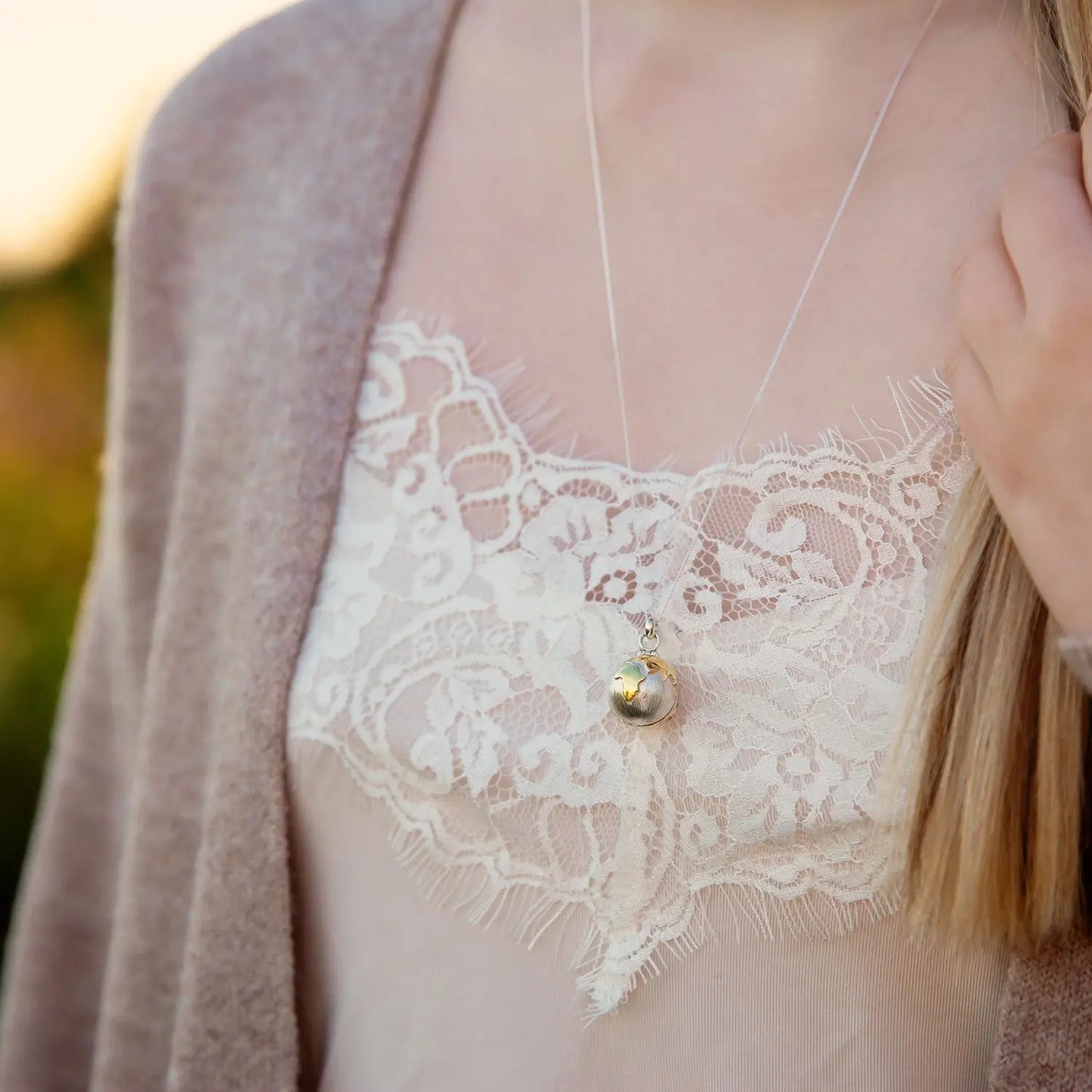 Personalised globe locket necklace worn on a model for scale
