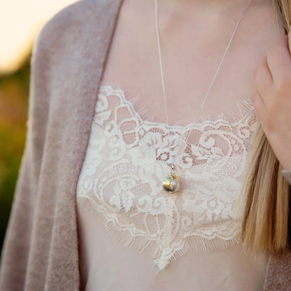 Personalised globe locket necklace worn on a model for scale
