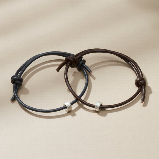 Dark brown and black leather cord bracelets with silver nut charms, featuring personalised engraving.
