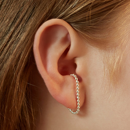Model wearing the sterling silver dotted cuff earrings that wrap round the ear.