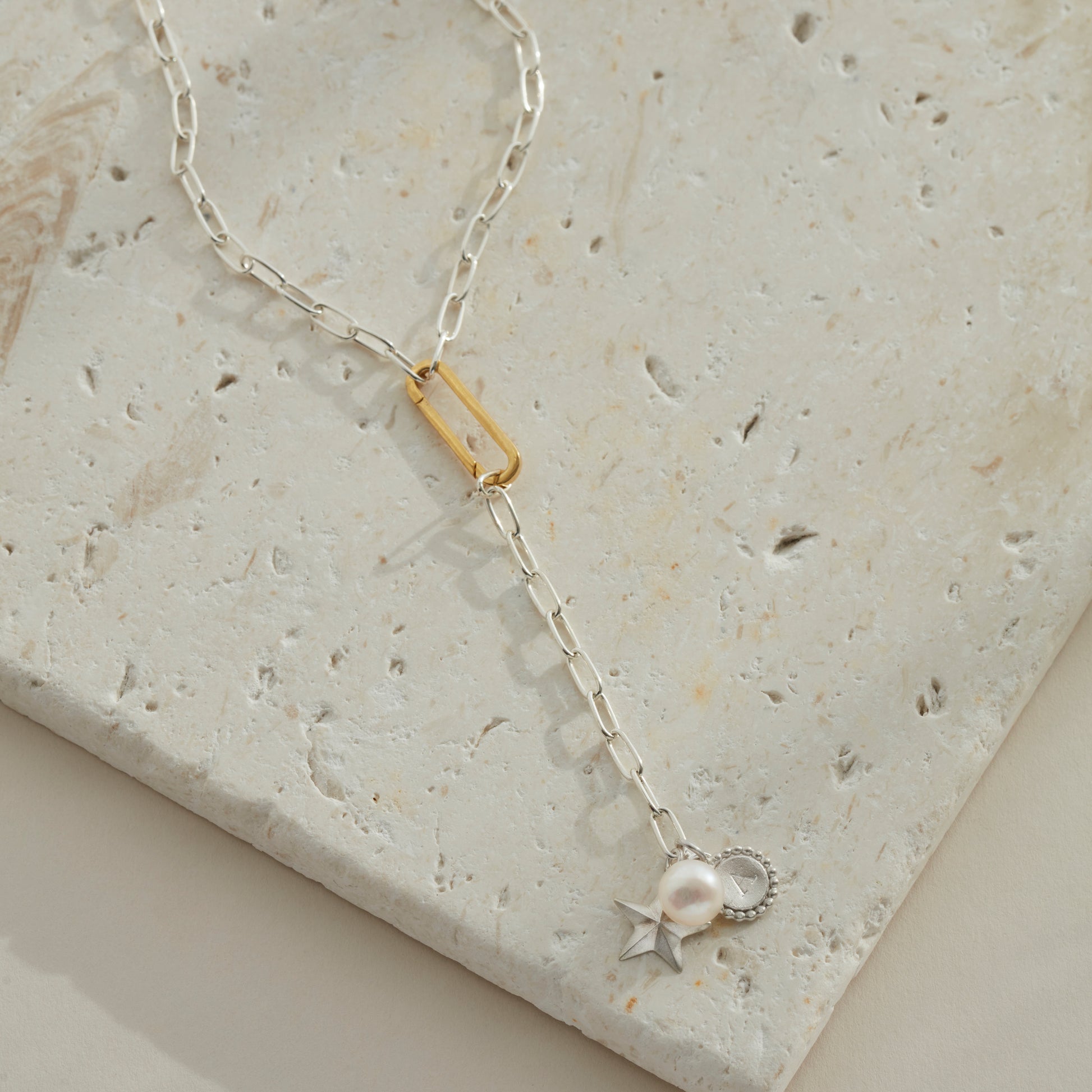 Silver lariat necklace with a star, pearl and initial charm at the end and connected with a gold vermeil clasp. 