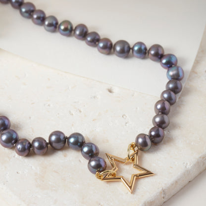 Peacock pearl necklace with 18ct gold vermeil star clasp, displayed on stone.
