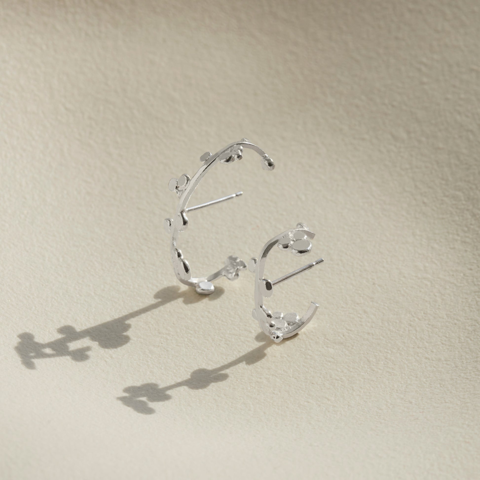 Two sizes of silver cuff earrings that wrap round the ear with dotted details. 