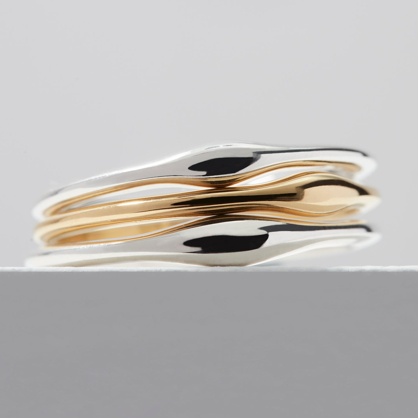 Slender Ripple Stacking Rings in sterling silver and 18ct gold vermeil, stacked together on a white background, showing their versatility as a stylish set.