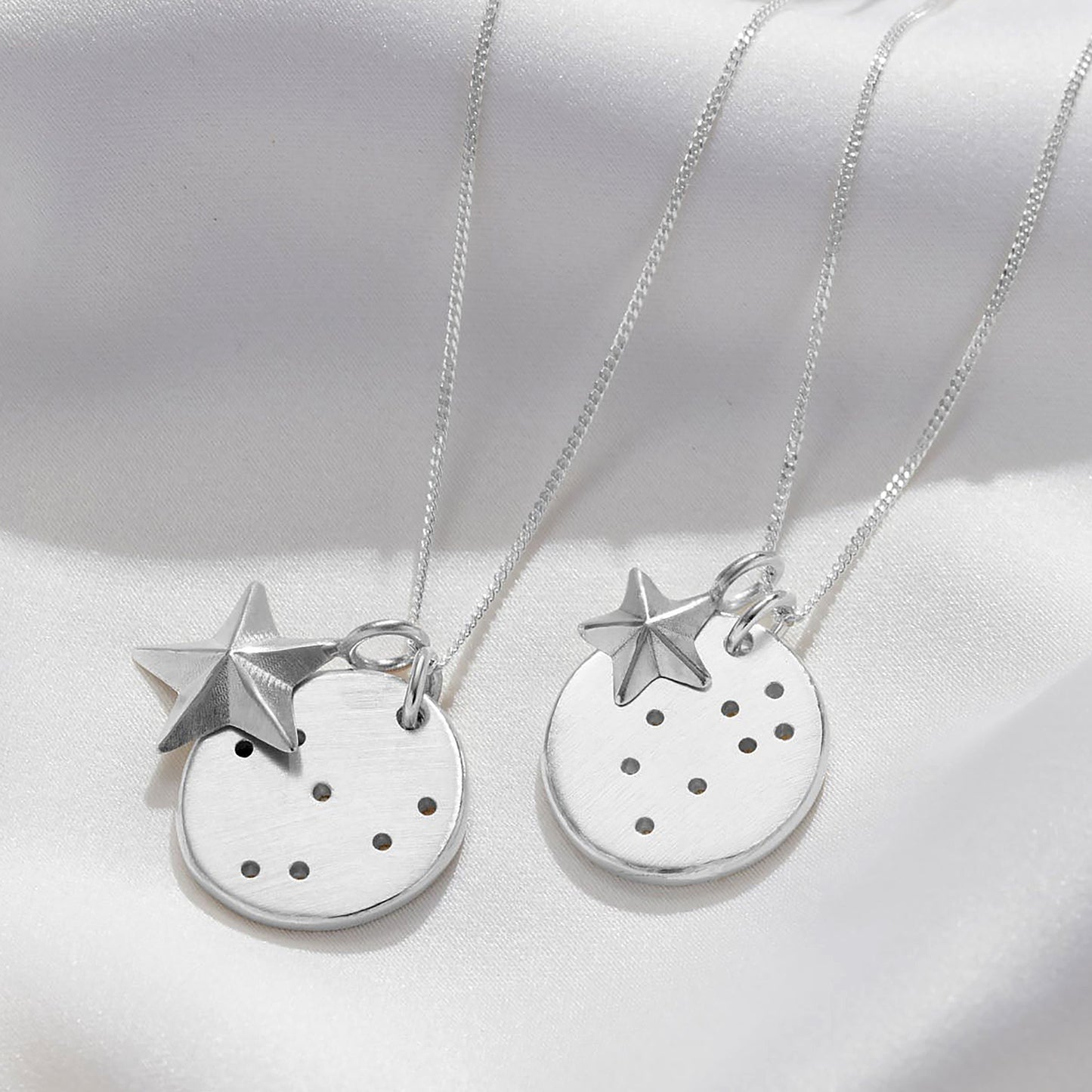 Close up of two different star signs displayed on Soremi's constellation disc necklace with the two options of large or small star charms.