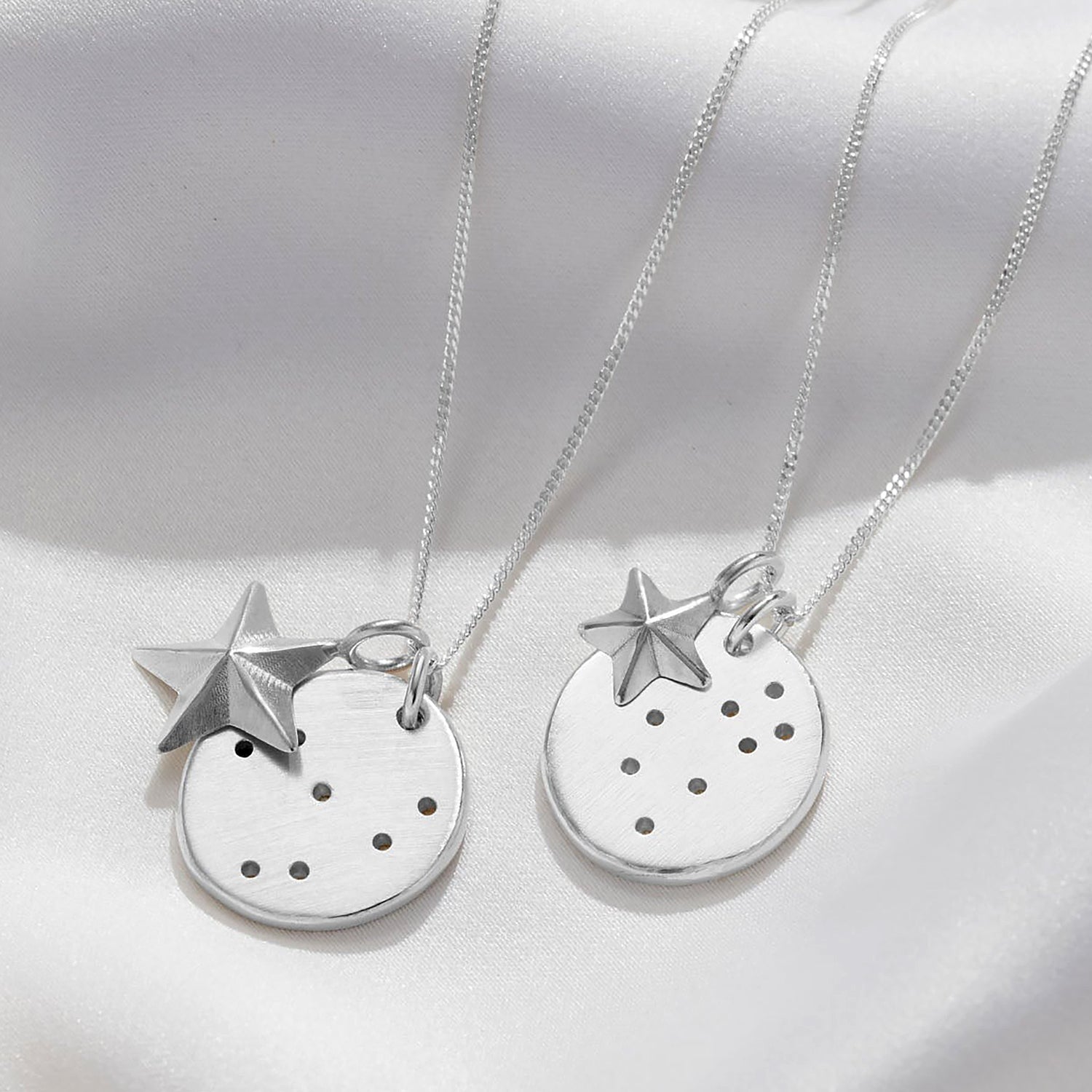 Close up of two different star signs displayed on Soremi's constellation disc necklace with the two options of large or small star charms.