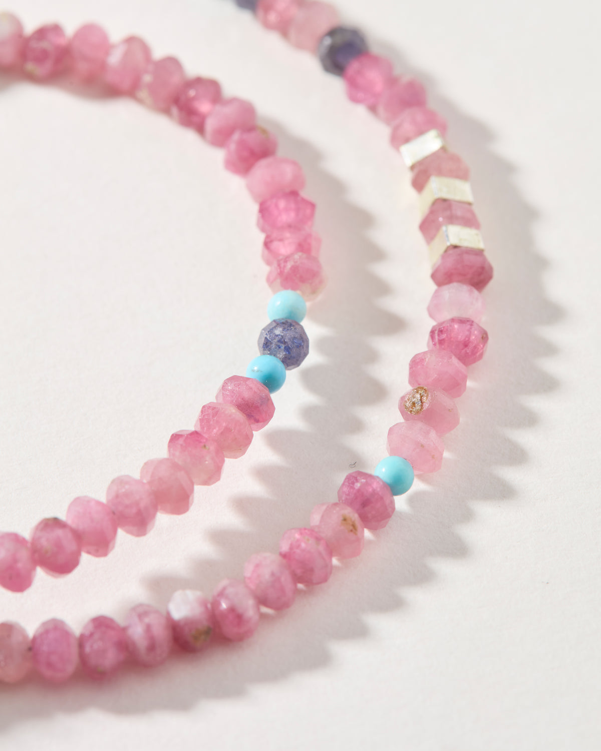 Close-up of faceted pink tourmaline beads with turquoise, violet and sterling silver accents