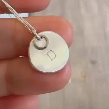 Hand-stamped silver nugget pendant showing its organic shape and 9ct gold detail