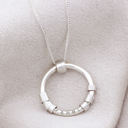 Close-up of sterling silver hidden message necklace with spinning beads around the circle pendant.
