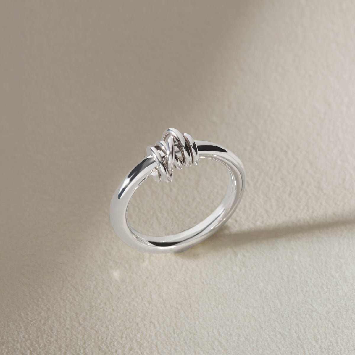 Handmade sterling silver knot ring showing polished band and overlapping silver knot detail