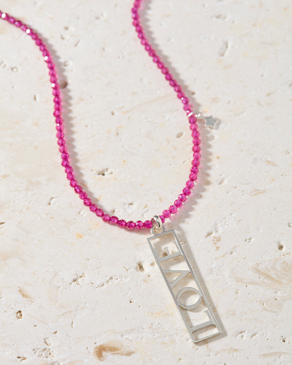 Close-up of openwork sterling silver LOVE pendant on natural ruby beaded necklace