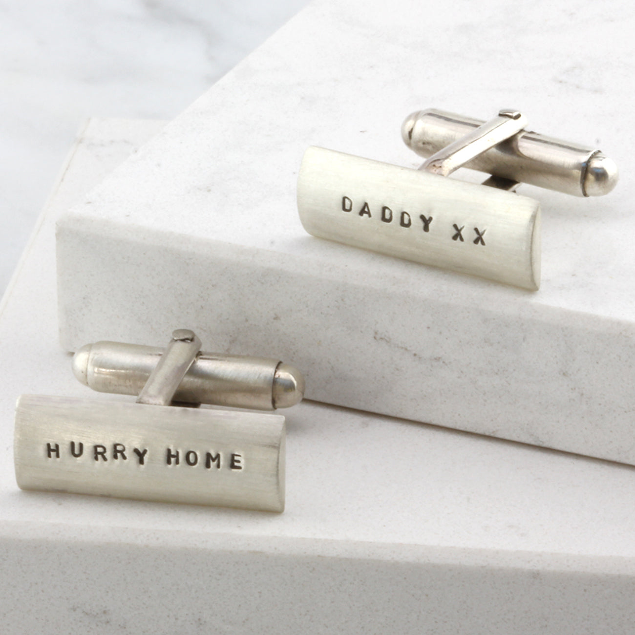 Detailed view of sterling silver cufflinks with personalised engraving that says 'Hurry Home' on one cufflink and 'Daddy xx' on the other.