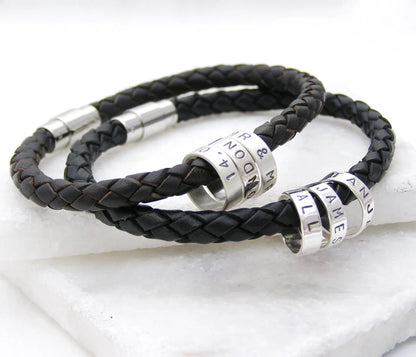 Two personalised men's braided leather bracelets with polished silver clasps and individually hand-stamped sterling silver hoops.